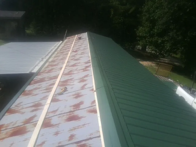 Old rusted panels beside newly installed green metal roofing — Wind Damage Roof Repair by Roofing Brothers in Blairs Mills