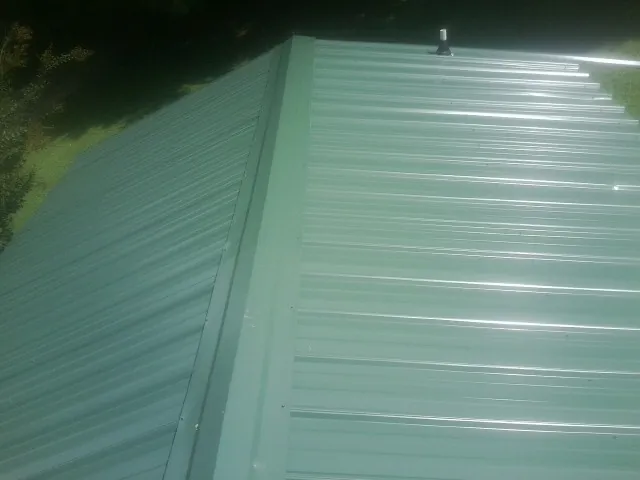 New green metal panels meeting at the ridge of a roof — Flat Roof Repair work by our crew in Blairs Mills