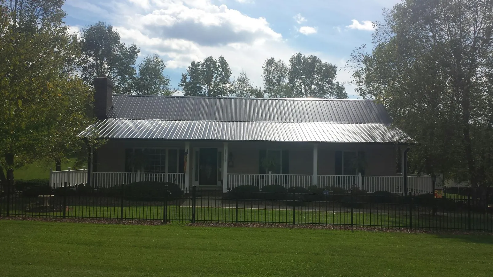 Gray metal roof on a brick ranch with a full width front porch — Gutter Guard Installation work by our crew in Blairs Mills
