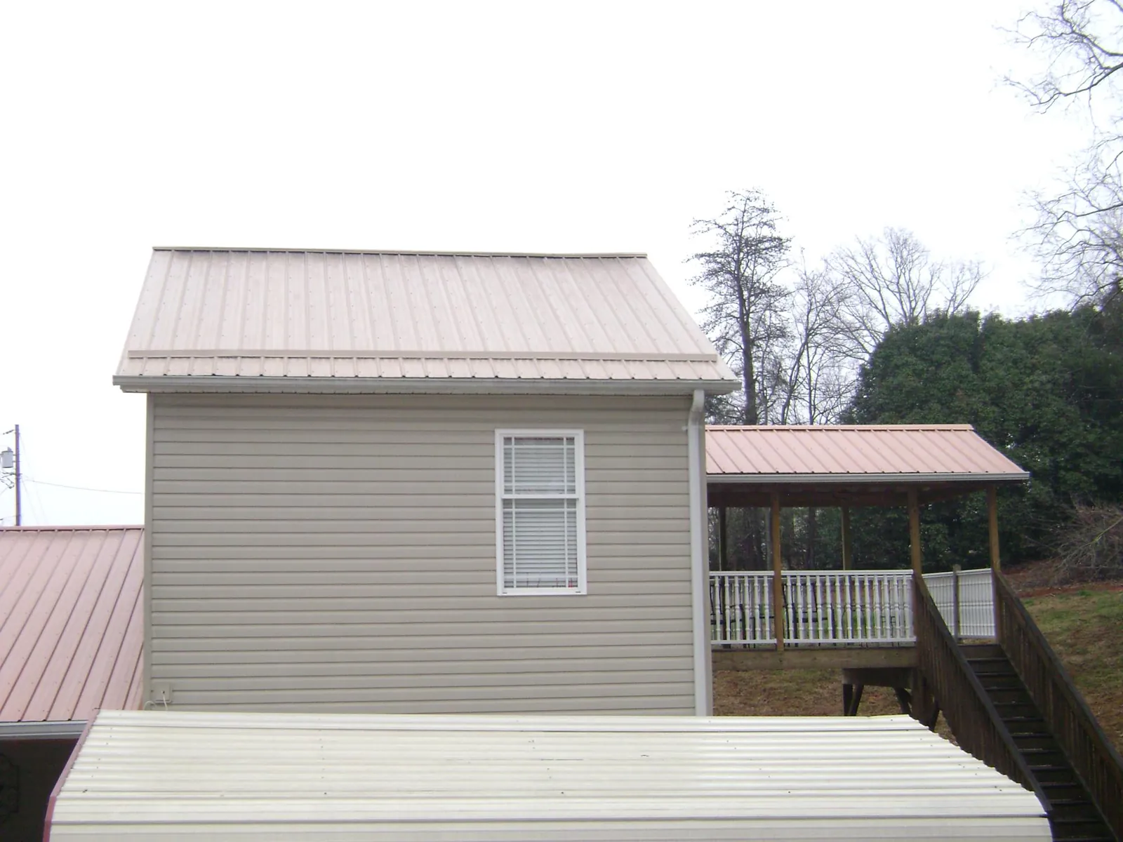 Tan metal roofs on a two story addition and attached porch, from a Roof Replacement job in Blairs Mills