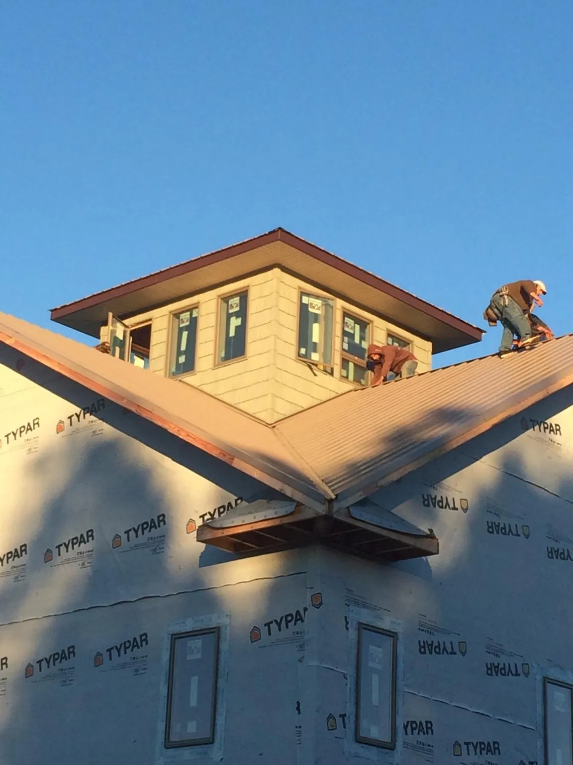 Roofers working around a rooftop cupola on a new metal roof at sunset — Roof Waterproofing in Blairs Mills by Roofing Brothers